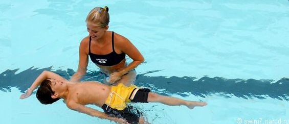тренер  учит  ребёнка плавать на спине